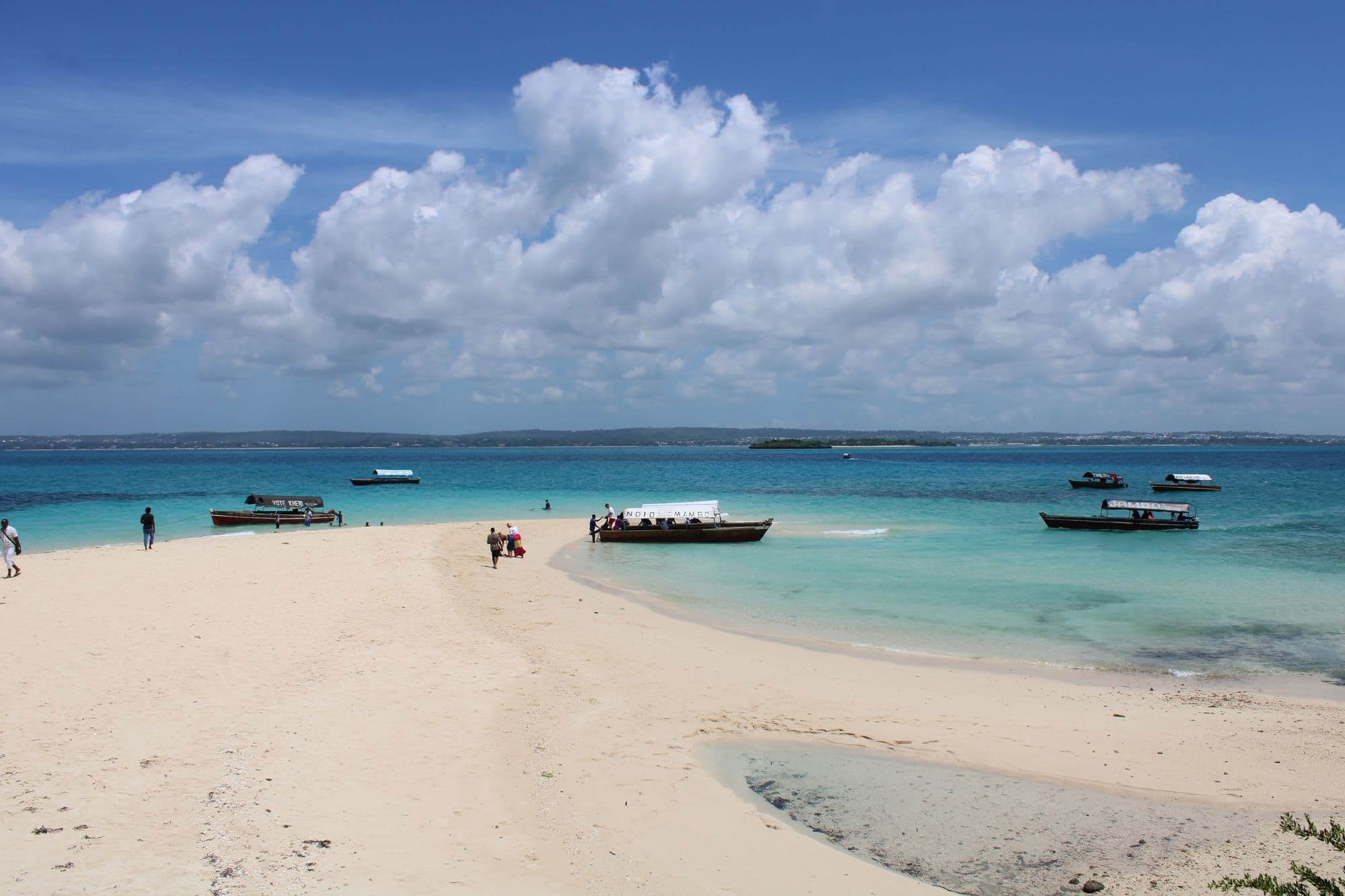 Dhows in turquoise water off a white sand beach in Zanzibar