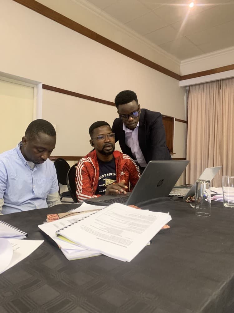 Nicolaus Novatus Mukasa working with partners on a laptop during a programme session